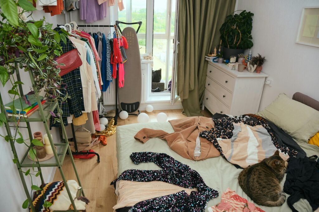 Messy bedroom with clothes scattered across the bed and floor