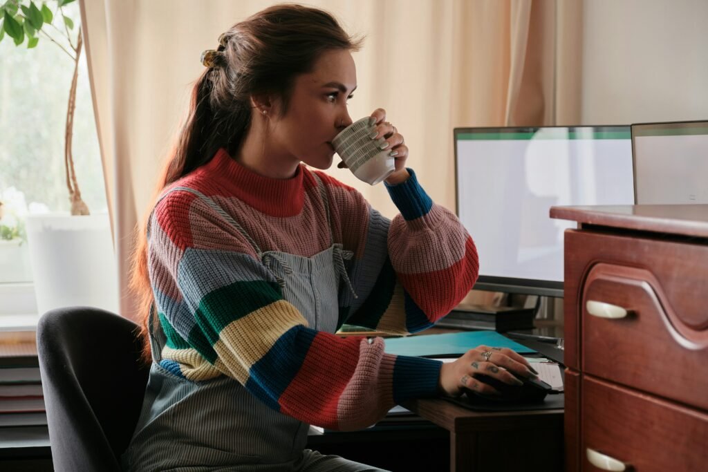 Woman drinking coffee while working at a home desk
