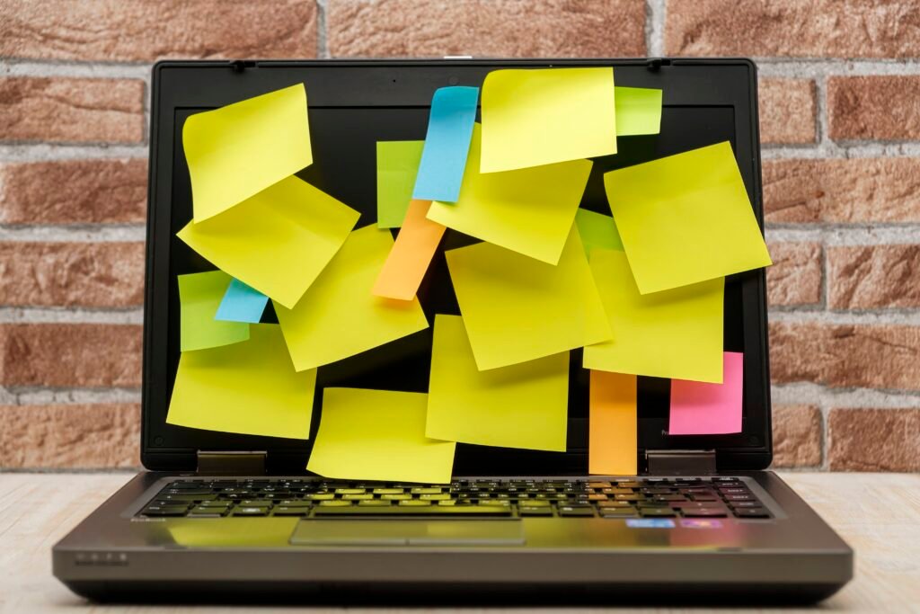 Laptop covered in colourful sticky notes representing an overcomplicated organisation system